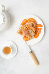 Homemade peach pie with teapot, cup of green tea and knife on white background. Top view.