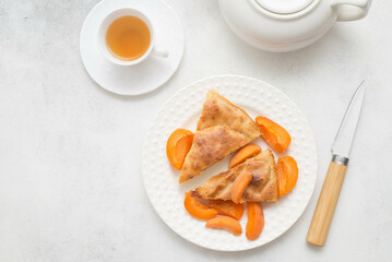 Homemade peach pie with teapot, cup of green tea and knife on white background. Top view.
