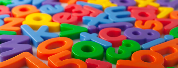 Plastic multi-colored alphabets letters on a magnet.
Lots of сolorful letters scattered on a white...