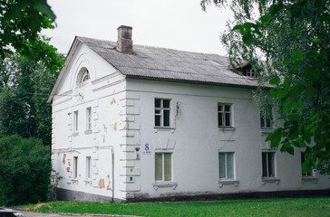 Abandoned white house with two floors in a green garden in a small town

