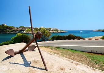 Wide angle view of big iron anchor near harbor of Porto Cristo town in Majorca island, Spain
