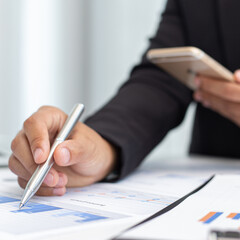 Financial businessmen use mobile phones to calculate income and analyze data about the company's financial performance to prepare for presentation to customers, Tax and accounting system concept.