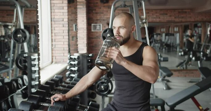 Tired athlete drinks water during training
