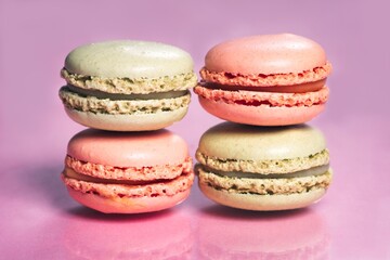 Stack of tasty french macarons on a pink pastel background.
