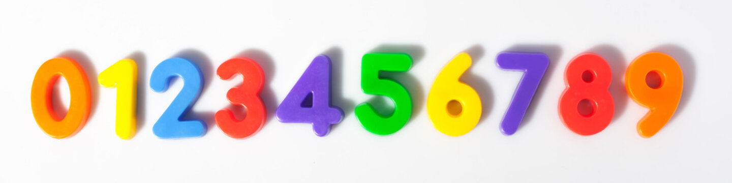 Multi-colored plastic magnetic numbers on a white background from 0 to 9 top view sequentially.