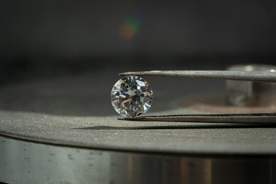 close up photo of round Diamond in Tweezers on polishing surface
