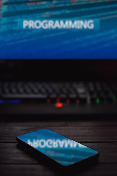 monitor reflected in smartphone with the word programming