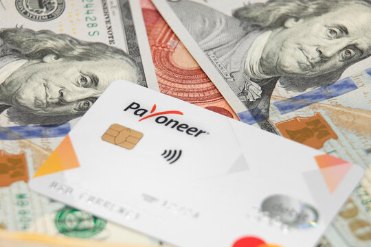 Gomel, Belarus - August 27, 2022: payoneer card with money in the background. Transfer and payment using mastercard.