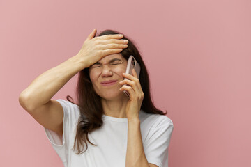 a very puzzled woman stands with her eyes closed in shock with her hand on her forehead and talks on the phone