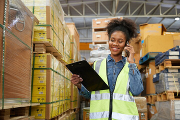 factory worker holding a clipboard and talking on smartphone to customer in warehouse factory
