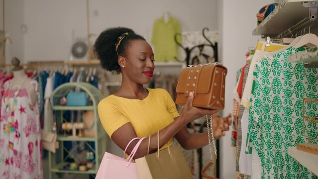 African american woman customer smiling confident holding handbag at clothing store