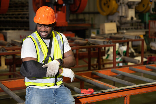 African factory workers or engineer wearing bandages splint, pain in elbow and ache in arm from hard work in the factory