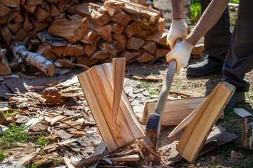 Axe chopping wood trunks. Man in gloves сhopping Wood with an explosion of Dust. Axe cutting wood block. Harvesting firewood on the winter
