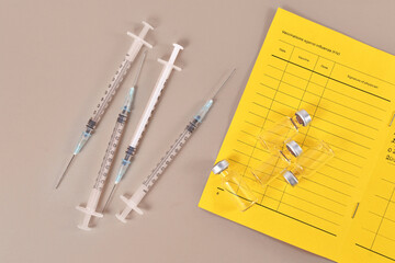 Concept for Corona virus booster vaccination showing vaccine passport with 4 syringes and vials