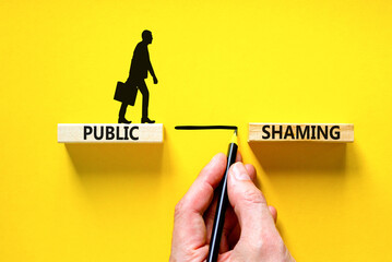 Public shaming symbol. Concept words Public shaming on wooden blocks on a beautiful yellow table...