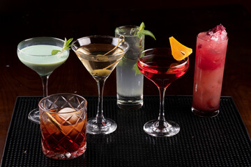 Collection of professionally prepared cocktails in rubber stand on pub counter