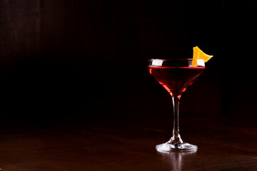 just a red martini drink with a glass and orange peel garnish viewed from the front in the corner