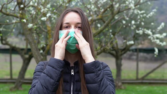 Woman in despair putting on protective medical mask and looking on camera with her deep sad eyes, person preparing herself for pandemic isolation due to virus infection spreading, wearing medical mask