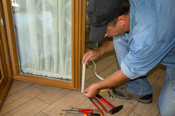 Picture of a handyman adding a gasket to a French door to improve the thermal insulation of his...