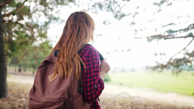 travel adventure. girl hiker walks with a backpack through the woods park back view. trekking adventure concept. girl tourist travels with a backpack outdoors in the park lifestyle