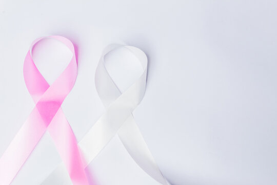 Pink ribbon fight against breast cancer and white ribbon to fight violence against women on isolated white background with space for text.