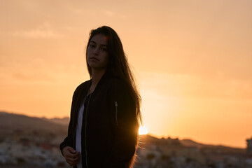 Fototapeta premium young hispanic girl posing at the rocks of a beach in the mediterranean sea while sunrise