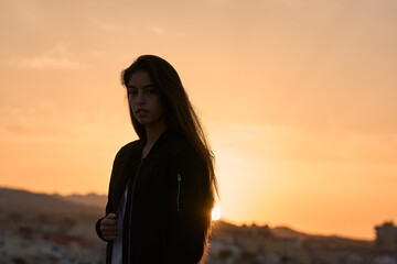 Fototapeta premium young hispanic girl posing at the rocks of a beach in the mediterranean sea while sunrise
