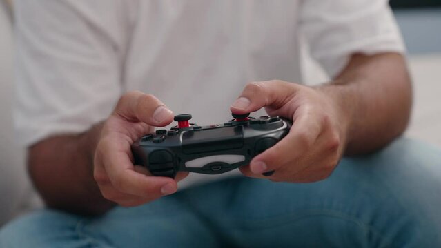 Young hispanic man playing video game sitting on sofa at home
