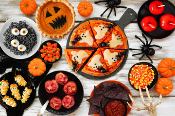Fun Halloween dinner party table scene over a white wood background. Top down view. Ghost pizza,...