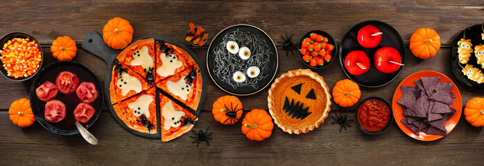 Fun Halloween dinner party table scene over a dark wood banner background. Above view. Pizza, jack...