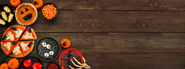 Fun Halloween dinner party corner border over a dark wood banner background. Above view. Pizza,...