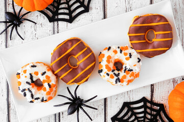 Spooky Halloween themed donuts. Above view table scene on a white wood background.