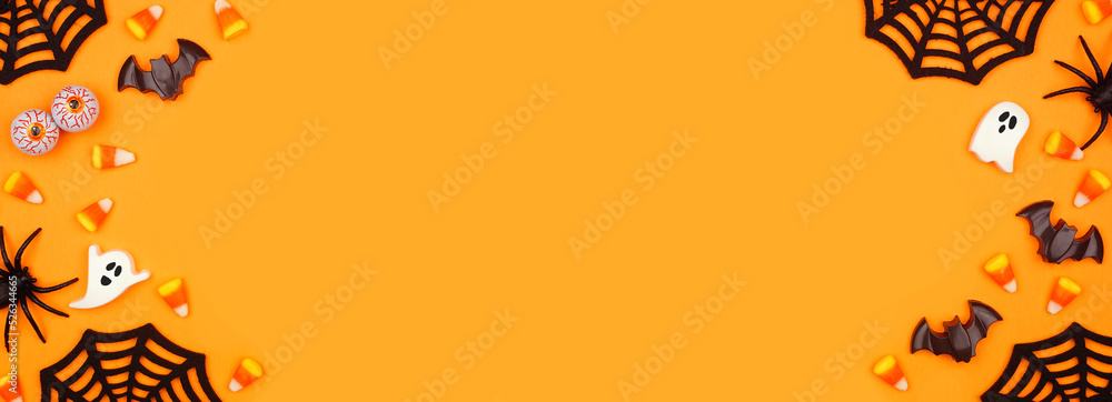 Poster halloween double border of scattered candy and decor. top view over an orange banner background with