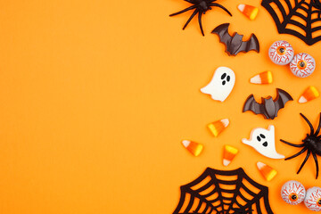 Halloween side border of scattered candy and decor. Overhead view over an orange background with...