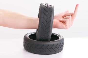 Man hand shows a middle finger through a small scooter tires on a white background. Scooter....