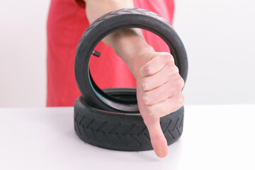 Male in a red t-shirt shows a thumb down through a small scooter tires on a white background....