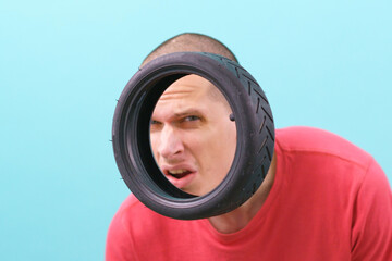 A man with twisted face looking at a small scooter tire on a blue background. Scooter. Service....