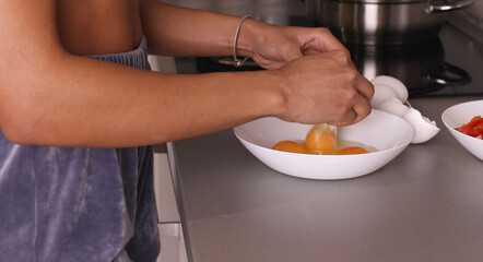Woman cracking eggs into glass bowl.
