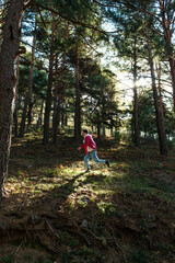 Caucasian man running in the middle of the nature wearing a red jacket