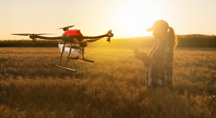 Woman farmer controls drone sprayer with a tablet. Smart farming and precision agriculture	