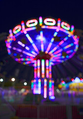 Carousel merry-go-round in amusement park at a night. Blurred colorful background.