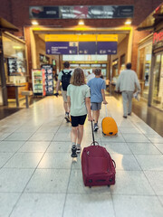 Teen girl with trolley walking in airport terminal