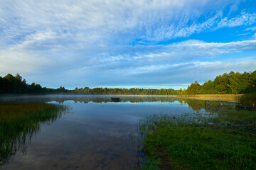 Fototapeta na wymiar Misty morning of early autumn on village lake 