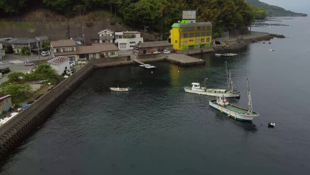 Aerial view of boats on the sea with a hill in the background in Numazu, Japan