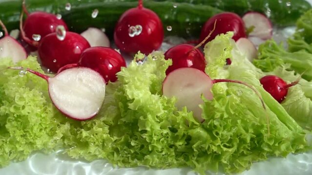 Radish, cucumbers and lettuce leaves in a stream of