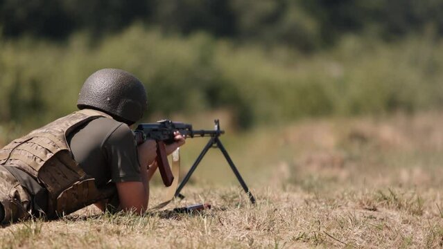 Armed man unloading machine gun with machine gun in his hands, soldier lying with gun, Military, Army war concept, ready to attack, Corps machine gun crew shooting, Army gunner attacking