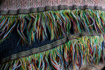 close up of woven fabric containing white, green, red, yellow dark blue, light blue, and black; textile