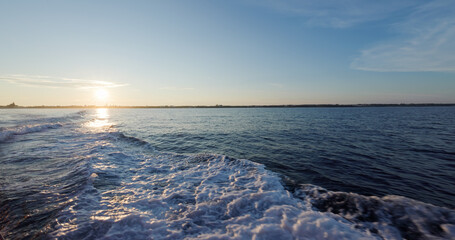 Back of the ship cruising over the sea at sunset time