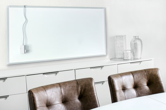 Weisse elektrische Infrarotheizung im Wohnraum mit Netzkabel und Thermostat