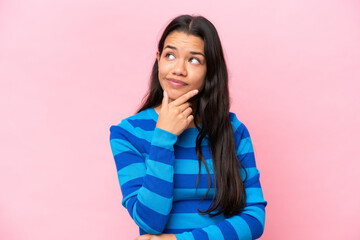 Fototapeta premium Young Colombian woman isolated on pink background having doubts